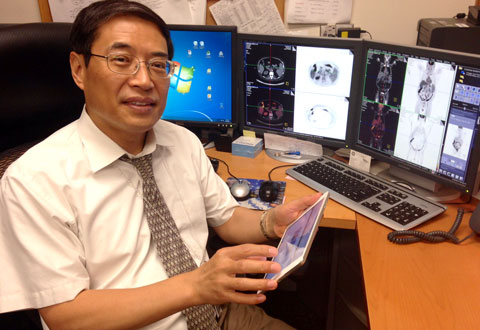 Dr. Frank Liu holds up his iPad at his office desk, demonstrating how he now has access to multiple screens.