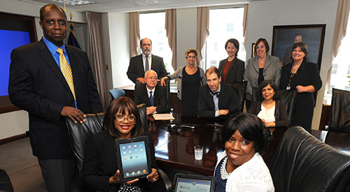 Washington, D.C. area Family Caregivers met with Dr. Petzel and other VHA leaders for the ceremonial launch of the VA Mobile Health Family Caregiver Pilot. (L to R) Front Row:  Lt. Col. Timothy Bostick, USA (Ret.) and  Caregivers Dellareece Bostickand Marcella Stretch; Middle Row: Dr. Robert Petzel, Under Secretary for Health; Dr. Neil Evans, Co-Director, VHA Connected Health; Dr. Madhulika Agarwal, Deputy Under Secretary for Health for Policy and Services; Back Row: Dr. Robert Jesse, Principal Deputy Under Secretary for Health; Kathleen Frisbee, Co-Director, VHA Connected Health; Laura Taylor, Director, Caregiver Support Program; Meg Kabat, Deputy Director, Caregiver Support Program; Gail Graham, Assistant Deputy Under Secretary for Informatics and Analytics.